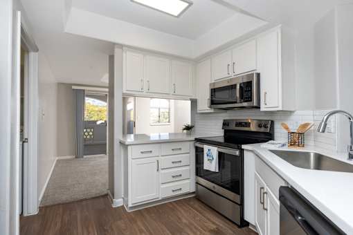 A modern kitchen with white cabinets and stainless steel appliances.