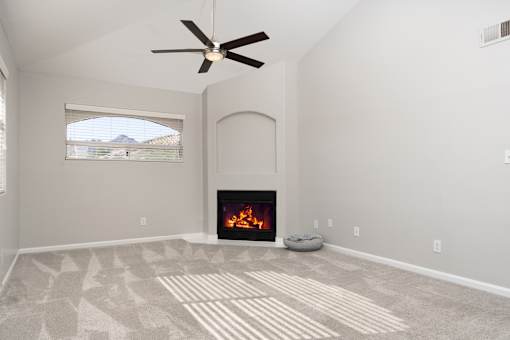 A living room with a fireplace and a fan.