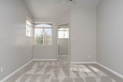 A room with a carpeted floor and a ceiling fan.