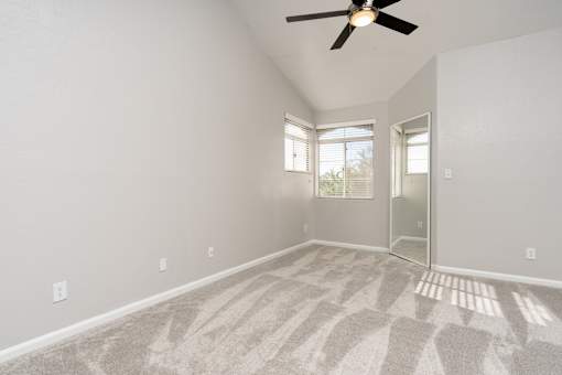 A room with a ceiling fan and carpeted floor.