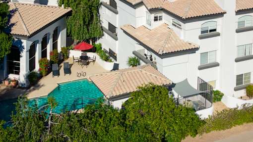 A white building with a pool in front of it.