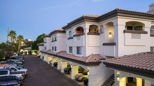 A row of houses with cars parked in front.