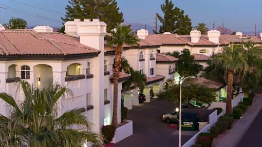 A street view of a residential area with houses and palm trees.