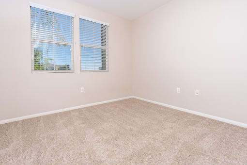 a bedroom with two windows and beige carpet