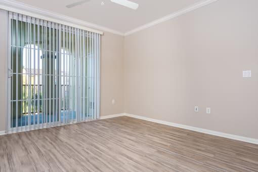 an empty bedroom with a large window and blinds