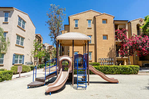 A playground with a brown slide and a blue and brown swing set.