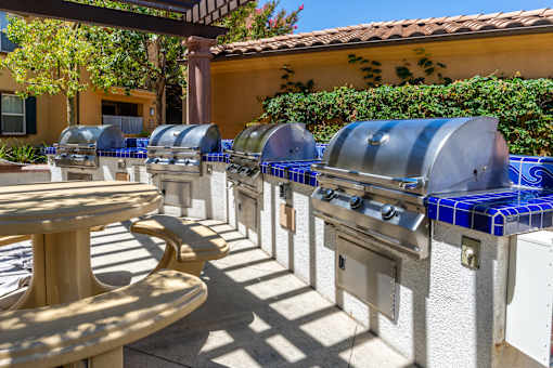 A row of outdoor grills are lined up on a patio.