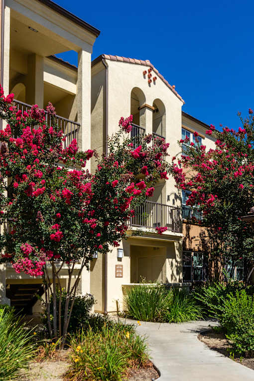 A building with a balcony and flowering plants in front.