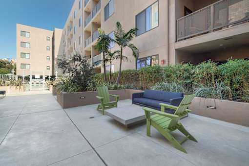 A patio with a couch, chairs and a table with a planter in between at Wilshire Valencia Apartment, Los Angeles