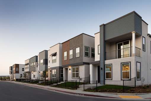 A row of modern townhouses with balconies and black railings.