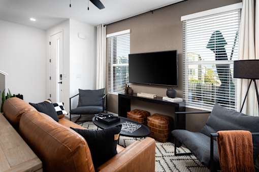 A living room with a brown leather couch, a black coffee table, and a television.