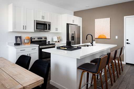 A kitchen with a white countertop and black chairs.