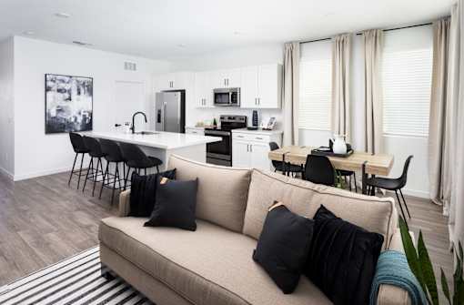 a living area with a couch table and chairs and a kitchen in the background