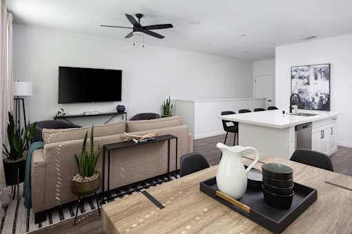a living room and kitchen with white walls and a large tv on the wall