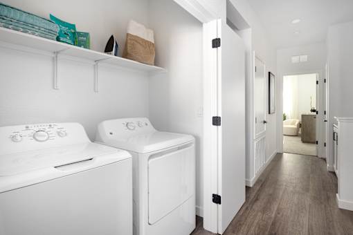 a white washer and dryer in a white laundry room with a wooden floor