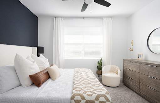 a bedroom with white bedding and a white dresser
