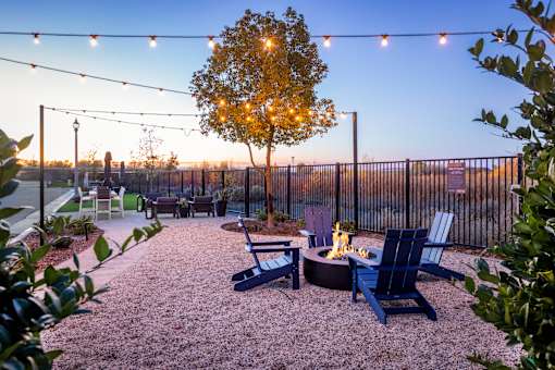a patio with chairs and a fire pit and lights