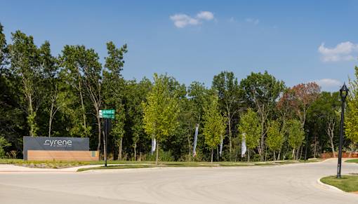 The entrance to a place called Cyrene is surrounded by trees.