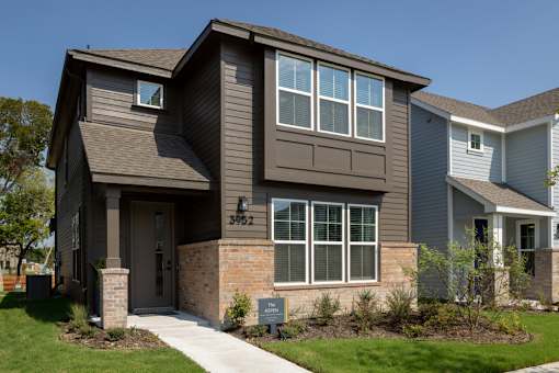 A house with a brown front porch and a brick pillar.