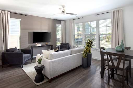A living room with a white couch, a television, and a dining table.