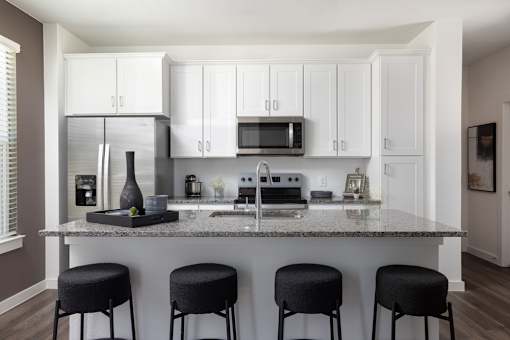 A kitchen with white cabinets and a marble countertop.