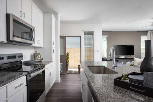 A modern kitchen with a black granite countertop and white cabinets.