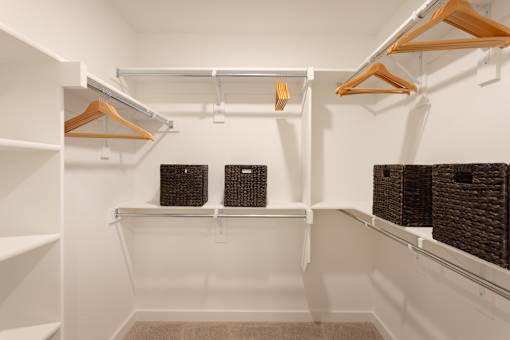 A white closet with two shelves and hangers.