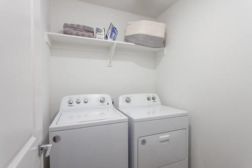 Two white front loading washing machines in a laundry room.