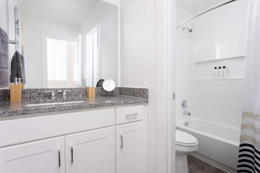 A bathroom with a marble countertop and white cabinets.