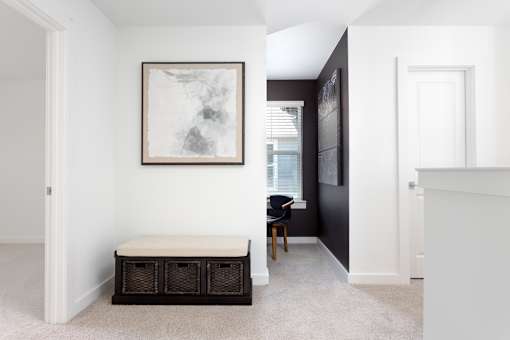 A hallway with a bench and a painting on the wall.