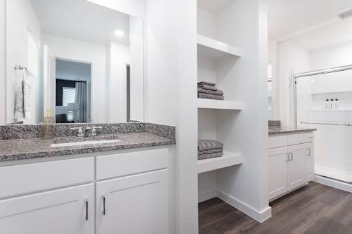 A bathroom with a sink, mirror, and towel shelf.