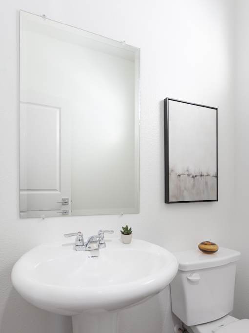 A white bathroom with a sink, toilet and mirror.