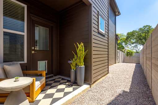 A small patio with a table and chairs is outside a house.