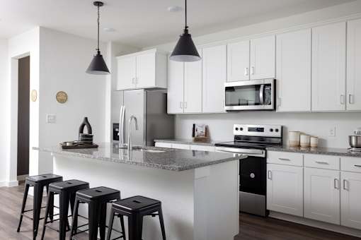 A kitchen with white cabinets and a grey island.