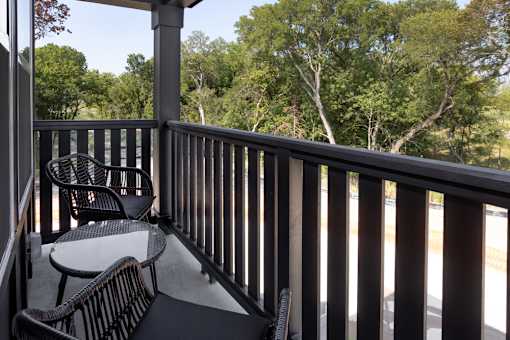A balcony with a table and chairs overlooking a wooded area.