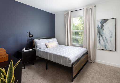 A bedroom with a bed, nightstand, and a painting on the wall.