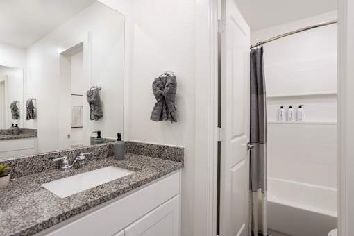 A bathroom with a sink, mirror, and towel rack.