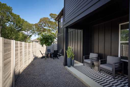 A patio with a black and white striped rug, two chairs, and a potted plant.