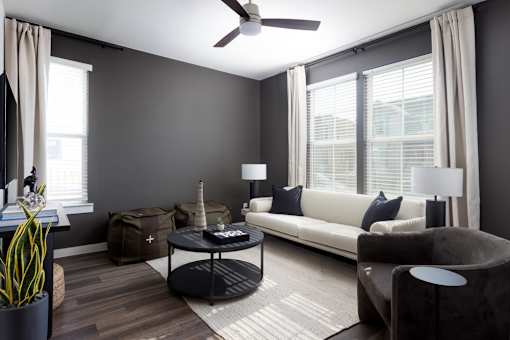 A living room with a white couch, a black coffee table, and a ceiling fan.