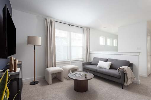 A living room with a grey couch, a coffee table, and a television.