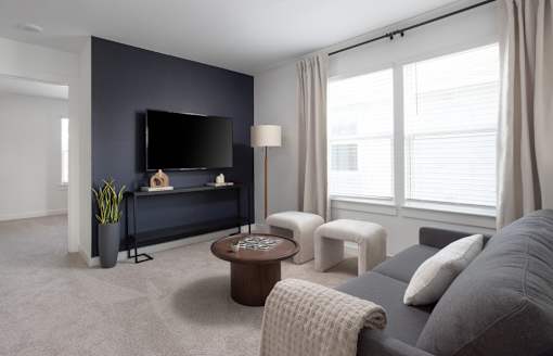 A living room with a grey couch, a black television, and a coffee table.