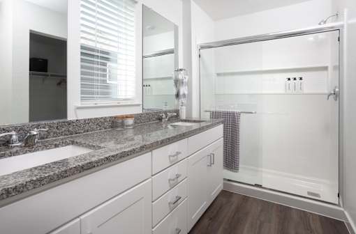 A bathroom with a sink, mirror, and shower.