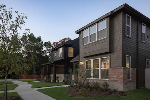 A modern house with a grey exterior and a brick pillar in front.