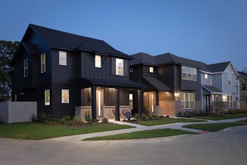 A modern house with a dark blue exterior and white trim is shown at dusk.