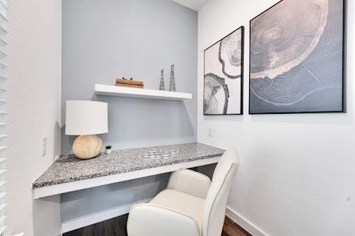 A white chair is in front of a desk with a lamp and a ball on it.