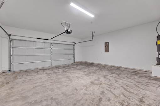 A large empty garage with a white door and a light on the ceiling.