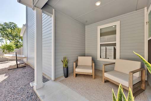 A patio with a couch, chair, and potted plant.