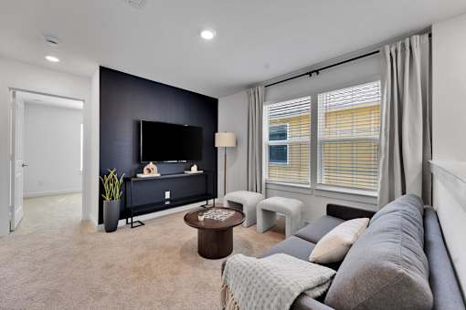 A living room with a grey couch, a coffee table, and a flat screen TV.