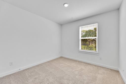 A room with a window and carpeted floor.