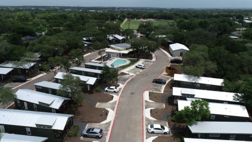 New Apartments in South Austin, TX - Casata Austin - Aerial View of Property Showing Apartment Homes, Driveway, Parking Spaces, Swimming Pool, and Green Spaces.